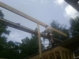 Carpenter setting a ridge beam over a new addition frame — Ice Dam Removal by Roofing Brothers in Jefferson Valley