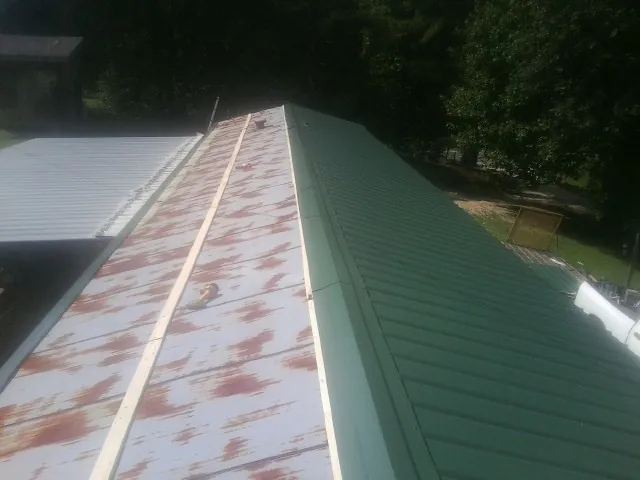 Old rusted panels beside newly installed green metal roofing — Wind Damage Roof Repair by Roofing Brothers in Jefferson Valley