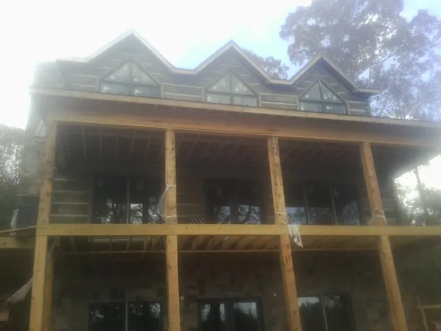Dormers and porch framing on a large log home under construction — Roof Coating work by our crew in Jefferson Valley
